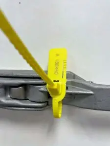 Combilock tamper evident security seal applied to a roll cage – pull-tight plastic seal with tear-off tag for logistics and asset protection